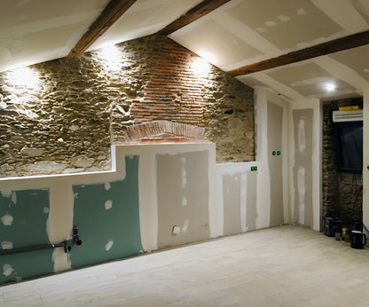 Futur cuisine avec pierre apparente en cours d’aménagement dans une grange rénovée aux Sorinières, placo terminé et sol posé