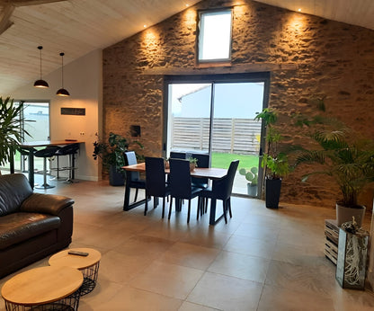 Salon rénové avec murs en pierre apparente dans une ancienne grange à Saint Philbert de Grand Lieu (44)